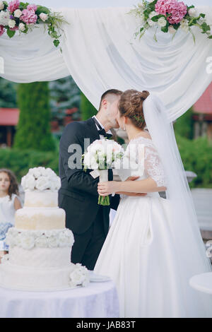 the bride and groom standing near a large wedding cake Stock Photo