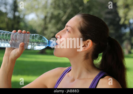 Eine junge Frau trinkt Wasser aus einer Flasche beim Sport oder Laufen Stock Photo