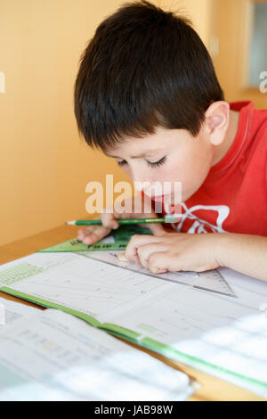 boy doing school homework from mathematics, geometry in workbook Stock Photo