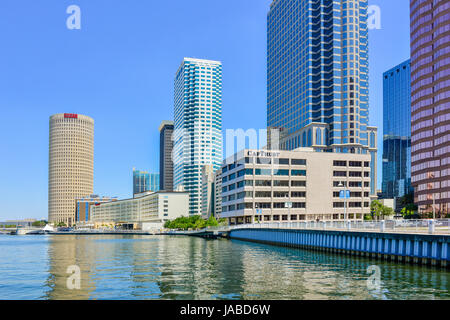 Tampa River Walk pedestrian pathway winds alongside the Hillsborough River waterfront with office buildings & skyscrapers in downtown Tampa, FL Stock Photo