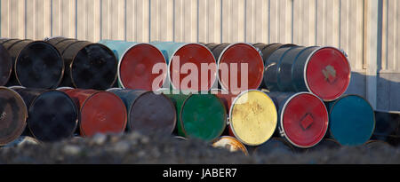 Colorful 50 gallon metal drums seen on end with one row stacked on the other against a metal building. Shallow depth of field. Stock Photo