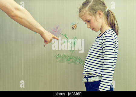 Little girl spoiled the wallpaper and her dad is angry. Stock Photo