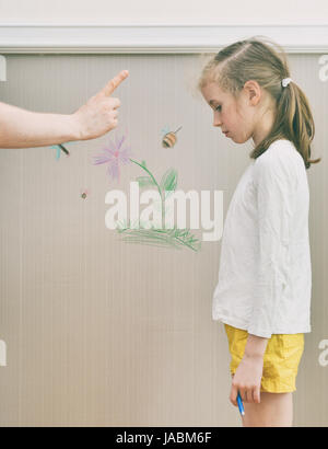 Little girl spoiled the wallpaper and her dad is angry. Stock Photo