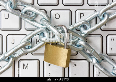 Locked chain on computer keyboard as symbol for danger in internet Stock Photo