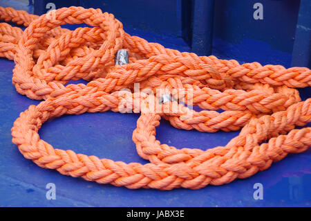 The reel of orange rope on dark blue paint background. Ship equipment. Stock Photo