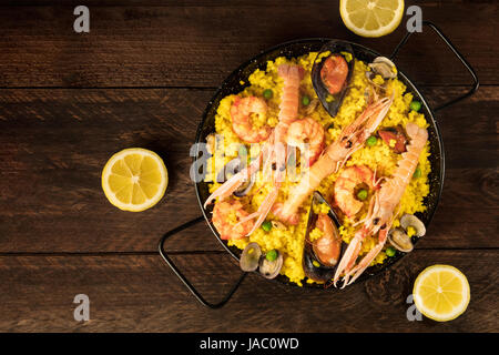 Spanish seafood paella in paellera, with lemons Stock Photo