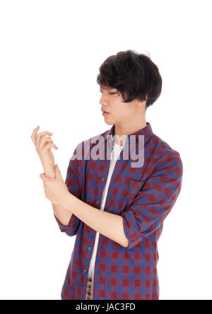 A young Asian man standing in a checkered shirt holding his painful arm and is worried, isolated for white background. Stock Photo