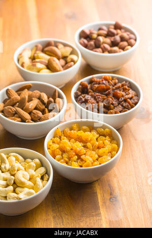 Various nuts and raisins in bowl on wooden table. Stock Photo