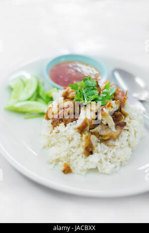 Thai crispy chicken served on steamed rice with sweet chilli sauce and cucumber slices. Traditional south east asian cuisine. Stock Photo