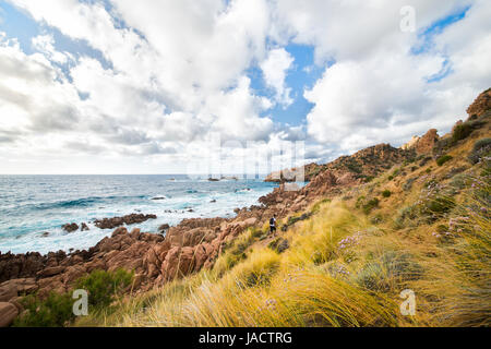 A man with a backpack is hiking along the trail coast of Sardinia in Italy Stock Photo