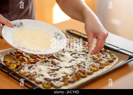preparing, baking plum cake, adding crumb to plums on dough Stock Photo