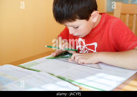 boy doing school homework from geometry mathematics in workbook Stock Photo