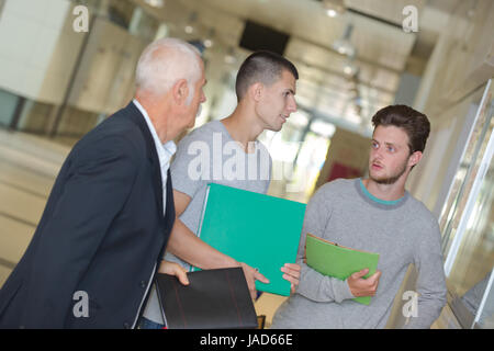 male teacher walking in corridor with students Stock Photo