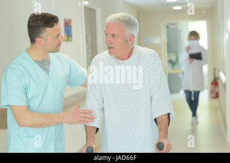 male doctor is helping older patient with crutches Stock Photo