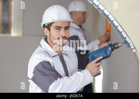 confident worker drilling a hole in the wall Stock Photo