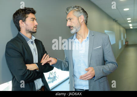 business partners talking when standing in office corridor Stock Photo