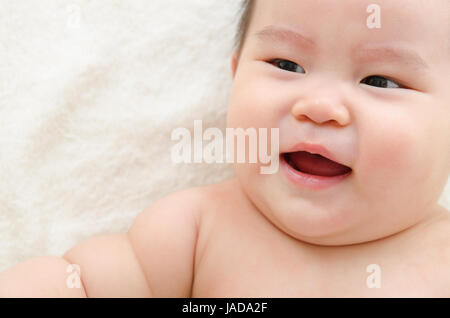 Upset Asian baby boy crying, lying on bed. Stock Photo