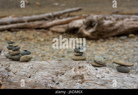 Small piles of stacked stones on a driftwood log at Ruby Beach on Washingtons Pacific Coast Stock Photo