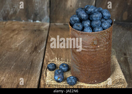 blueberries in rusty tin can on burlap and rustic barn wood Stock Photo