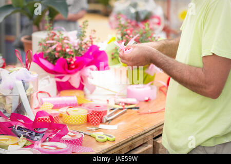 closeup florist making a ribbon bow. Shallow depth of field, focus on hand Stock Photo