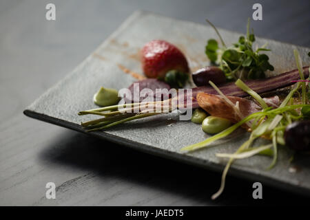 Close up of salad on stone tray at table in cafe Stock Photo