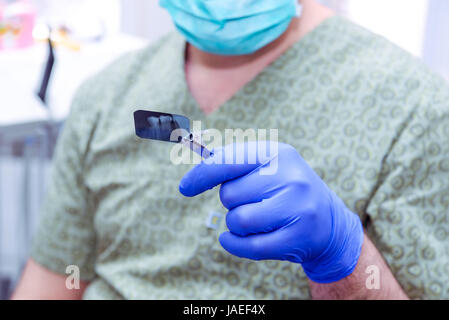 Close-up Male Dentist doctor looking and examines Teeth X-ray shot. Selective focus. Stock Photo