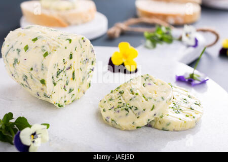 Herb butter with edible flowers on marble cutting board, healthy food. Stock Photo