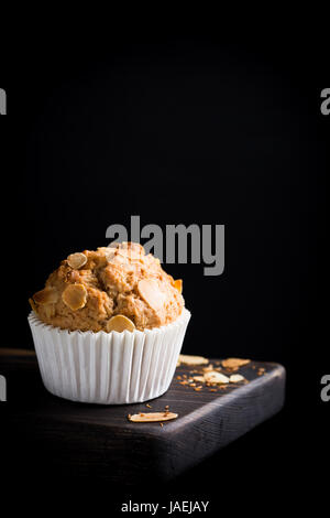 Delicious homemade coconut cinnamon muffin with almond flakes on black background. Healthy food concept with copy space. Stock Photo