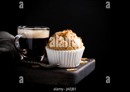 Delicious homemade coconut cinnamon muffin with almond flakes on black background. Healthy food concept with copy space. Stock Photo