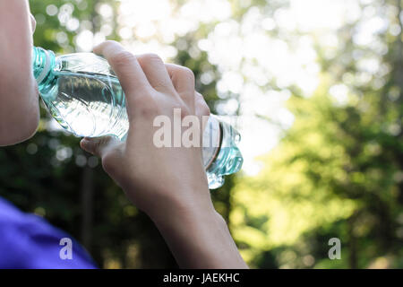 Woman drinking mineral water and resting while jogging in the park Stock Photo