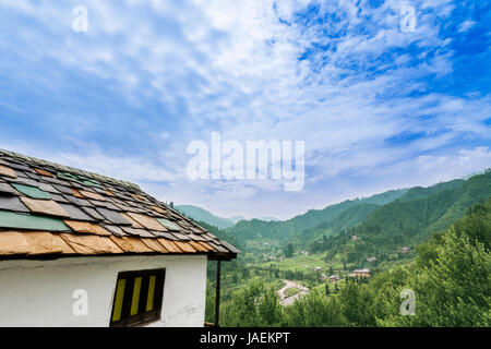 Idyllic landscape of the Janjehli valley and multicolor roofed hut under a beautiful blanket of bright blue sky. Stock Photo