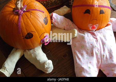 Two pumpkins dressed up as princess babies with pacifiers, seen from above. Stock Photo