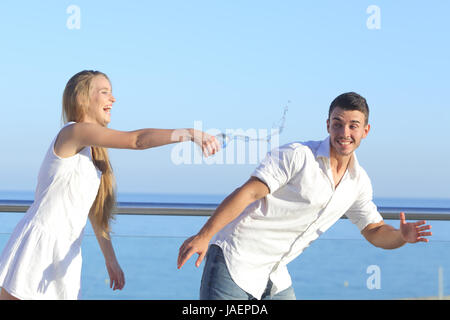Woman throwing water to her boyfriend with the sky in the background Stock Photo