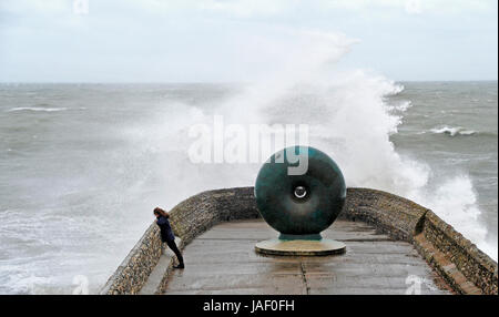 Brighton, UK. 6th June, 2017. A woman watches waves crash over Brighton seafront as storms with high winds and driving rain batter the south coast of Britain today with more unsettled weather forecast for the next few days Credit: Simon Dack/Alamy Live News Stock Photo