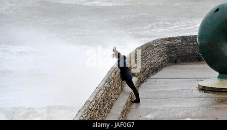 Brighton, UK. 6th June, 2017. A woman watches waves crash over Brighton seafront as storms with high winds and driving rain batter the south coast of Britain today with more unsettled weather forecast for the next few days Credit: Simon Dack/Alamy Live News Stock Photo