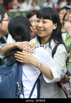 Shanghai, China. 7th June, 2017. A teacher (1st R) hugs an examinee of the national college entrance examination outside the exam venue at No. 54 High School in Shanghai, east China, June 7, 2017. A total of 9.4 million Chinese students sit the annual national college entrance examination from Wednesday. Credit: Ding Ting/Xinhua/Alamy Live News Stock Photo