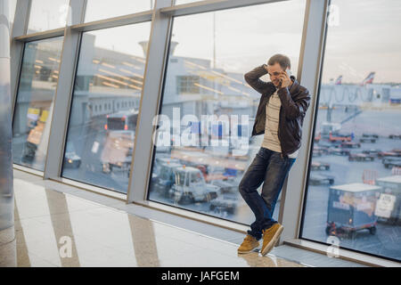 Gonna be home soon. Portrait of a handsome young man laughing speaking on the phone while waiting for his flight at the airport lounge Stock Photo
