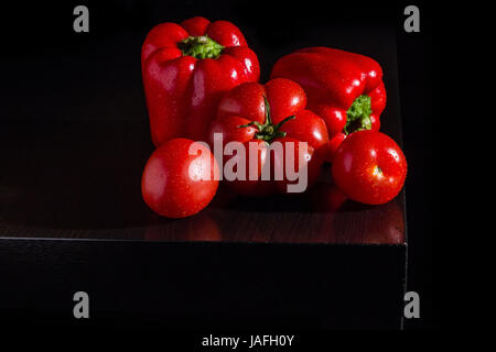 Three big jucy bell peppers and fresh tomatoes on dark wooden background Stock Photo