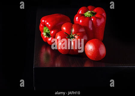 Three big jucy bell peppers and fresh tomatoes on dark wooden background Stock Photo