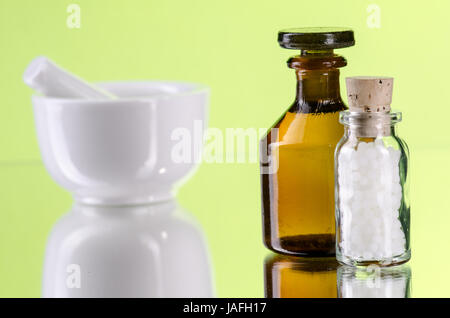 homeopathic pills with glassbottle and mortar, green background Stock Photo