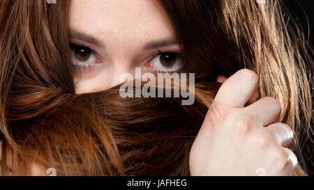 Close-up portrait of a beautiful woman covers the face by long brown hairs