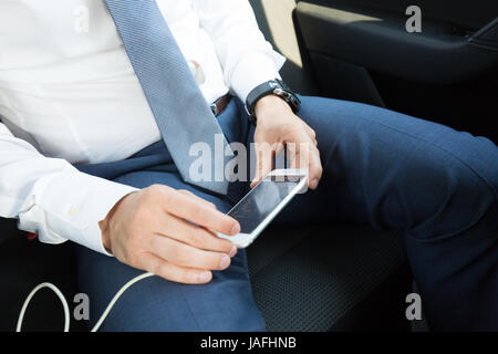 Close up of businessman using mobile smart phone in a car. Stock Photo