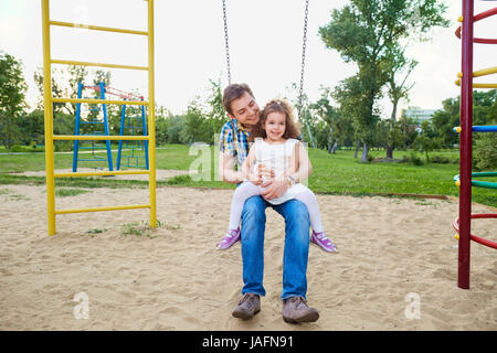 Father with  child on a swing at the playground Stock Photo