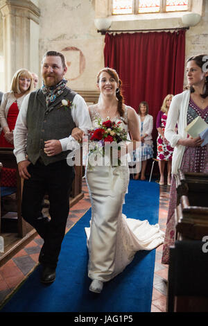 Smiling bride and groom walking down the isle in a church. Stock Photo