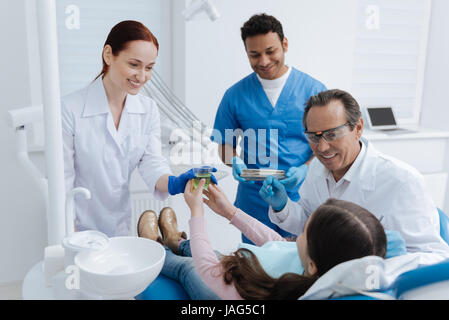 Nice conversation. Positive delighted intern keeping smile on her face holding glass in left hand while standing in front of girl Stock Photo
