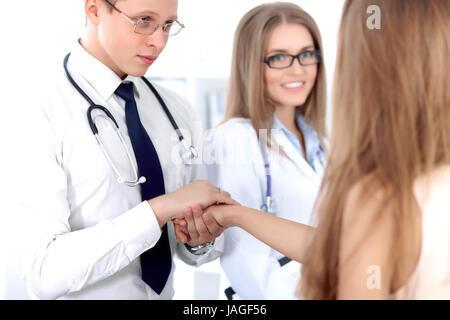 Friendly male doctor and female patient shaking hands.  Stock Photo