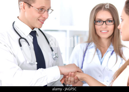 Friendly male doctor and female patient shaking hands.  Stock Photo