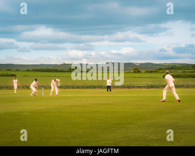 Game of Cricket being played in typical British village of Sessay with the White Horse in the background. Stock Photo