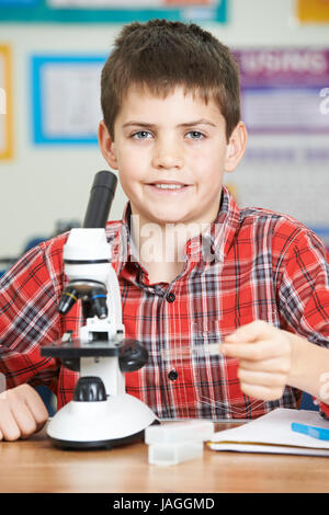 Male Pupil Using Microscope In Science Lesson Stock Photo