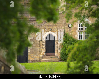 Door in stone wall seen through trees, Sessay, North Yorkshire, UK. Stock Photo